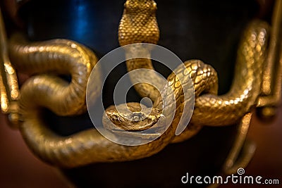 Closeup of chiseled and gilded snakes of old french bronze urn shaped clock at the Museum of Decorative Art Editorial Stock Photo