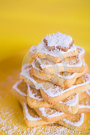 Closeup Christmas tree made from cookies in form of stars with coconut chips on yellow background. Stock Photo