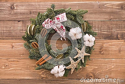 Closeup of Christmas wreath with cinnamon, cotton ears and ribbon decorations on wooden background Stock Photo