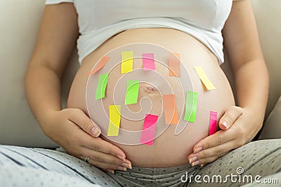 Closeup of colorful memo stickers on pregnant woman tummy Stock Photo
