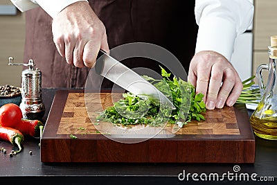 Closeup of a cook man cutting parsley, dill chopped Stock Photo
