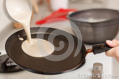 Closeup cooking pancakes on a gas stove. On a hot skillet liquid dough from the ladle is poured Stock Photo