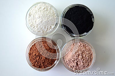 A closeup of cosmetic clays for detox face masks - French green clay, kaolin, pink clay, red clay and powdered activated charcoal Stock Photo