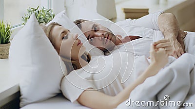 Closeup of couple with relationship problems having emotional conversation while lying in bed at home Stock Photo