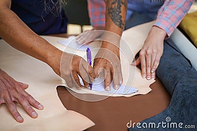 Closeup and crop hands of leather craftsman drawing design on white leather in order to sew into products Stock Photo