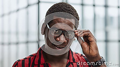 Closeup curious african man with adjusting his glasses for better vision, trying to peep secrets, spying. Stock Photo