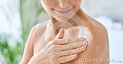 Closeup cut view of mid age woman applying body cream. Antiage skincare concept. Stock Photo