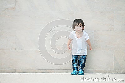 Closeup cute asian kid stand on marble stone wall textured background with copy space Stock Photo