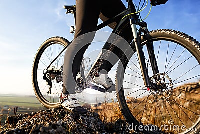 Closeup of cyclist man legs riding mountain bike on outdoor trail on hill Stock Photo