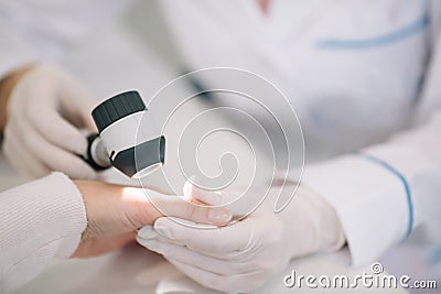 Closeup of dermatologist examining mole on hand of female patient in clinic Stock Photo