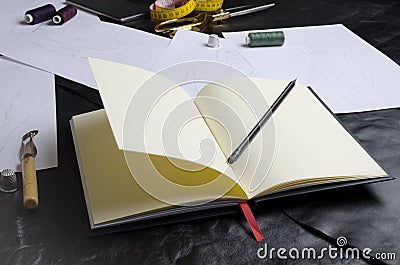 Closeup of designer`s notebook on table.Tools of designer during work.Concept of creating clothes collection Stock Photo