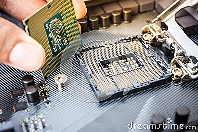 Closeup detail of CPU Chip over socket with hand of a modern computer black motherboard. Electronic small component details. Stock Photo