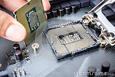 Closeup detail of CPU Chip over socket with hand of a modern computer black motherboard. Electronic small component details. Stock Photo