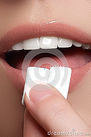 Closeup detail of woman putting pink chewing gum into her mouth. Chewing Gum, Eating, Women. Close up on a beautiful girl Stock Photo