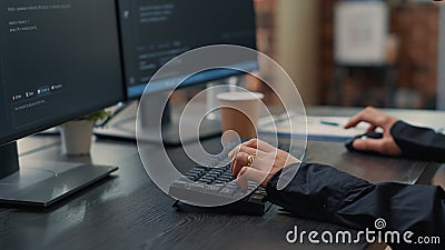 Closeup of developer hands typing code on keyboard while looking at computer screens Stock Photo