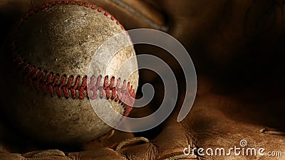Closeup of a dirty, old baseball with red seams on a brown leather glove. Stock Photo