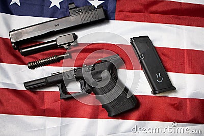 Closeup of disassembled pistol on the American flag. Gun laws in the USA. Handgun parts. Top view disassembly weapon. Stock Photo