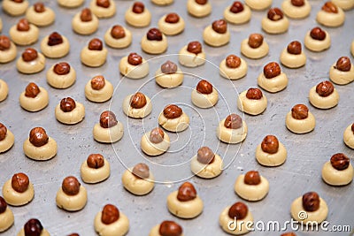 Closeup dmall shortbread cookies in the formround balls on baking sheet with paper, with hazelnut nuts in cookies center. Concept Stock Photo