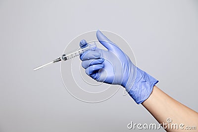 Closeup doctor's hand in rubber purple glove holding transparent syringe with closed cap. Isolated on white background. Concept Stock Photo