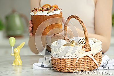 Closeup of Easter basket with painted eggs on white marble table near woman with cake, focus on food Stock Photo