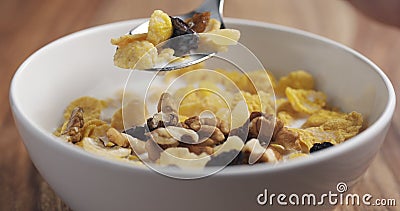 Closeup eating with a spoon breakfast with corn flakes and mix of nuts and fruits Stock Photo