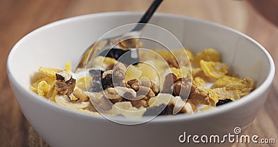 Closeup eating with a spoon breakfast with corn flakes and mix of nuts and fruits Stock Photo