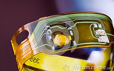 Closeup of electronic flexible printed circuit on plastic strip curled to ring on purple background Stock Photo