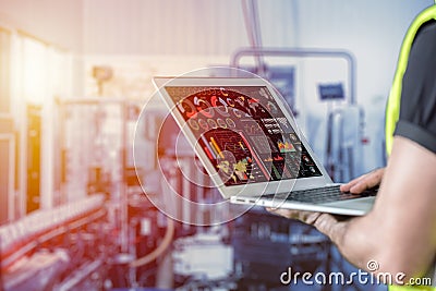 Closeup engineer using laptop computer to monitor and checking business data with blur factory background Stock Photo