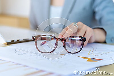 closeup eyeglasses and female hand on background laptop and grap Stock Photo