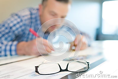 closeup eyeglasses on table man working in background Stock Photo