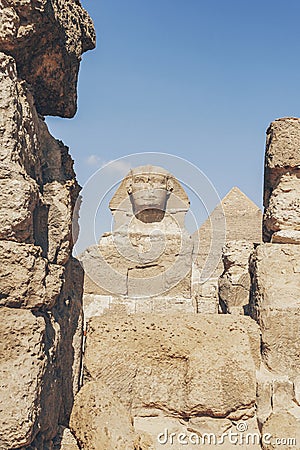 A closeup of the face of the Great Sphinx with pyramid in the background on a beautiful blue sky day in Giza, Cairo, Egypt. Stock Photo