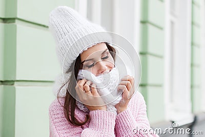 Closeup face of a young Smiling woman enjoying winter wearing knitted scarf and hat. Stock Photo