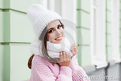 Closeup face of a young Smiling woman enjoying winter wearing knitted scarf and hat. Stock Photo