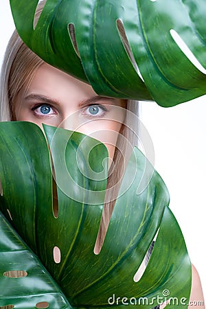 Closeup facial portrait personable woman holding green monstera. Stock Photo