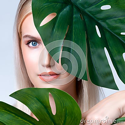 Closeup facial portrait personable woman holding green monstera. Stock Photo