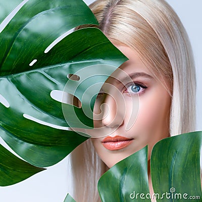 Closeup facial portrait personable woman holding green monstera. Stock Photo