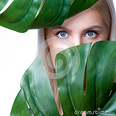 Closeup facial portrait personable woman holding green monstera. Stock Photo