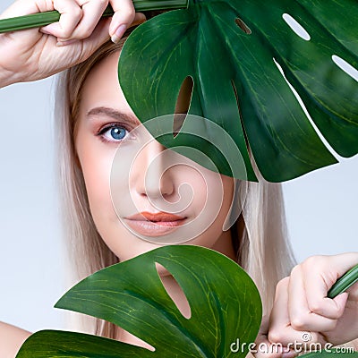 Closeup facial portrait personable woman holding green monstera. Stock Photo