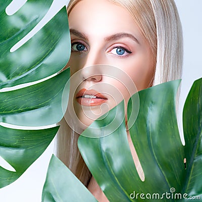 Closeup facial portrait personable woman holding green monstera. Stock Photo