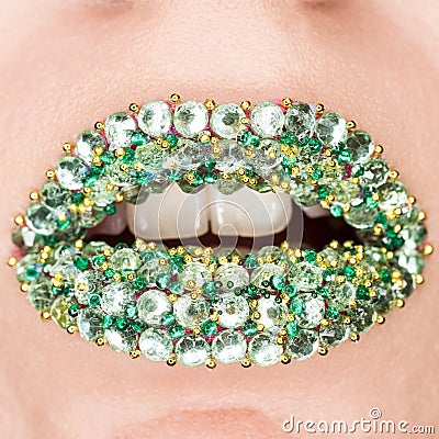 Closeup of Fashion Green Sexy Lips with green and gold gems on lips. Open Mouth. Make up, cosmetics, lip art Stock Photo