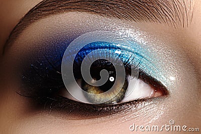 Closeup female eye with beautiful fashion bright make-up. Beautiful shiny blue eyeshadow, wet glitter, black eyeliner Stock Photo