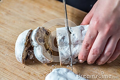 Closeup Female Hands Cutting Mini Marzipan Stollen with Knife on Wooden Board Stock Photo