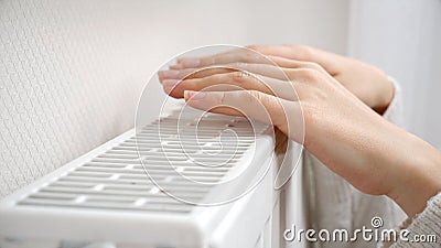 Closeup of female hands warming over the wall radiator at home Stock Photo