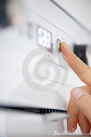 Closeup, finger and button on oven in kitchen for heating, preparation and appliance for baking. Person, press or switch Stock Photo