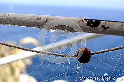 Closeup of a fishing net hang on a white pole on a ship at the seaside with a blue background Stock Photo