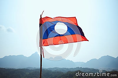 Closeup of the flag of Laos under the sunlight surrounded by mountains in Nam Xay in Vang Vieng Stock Photo
