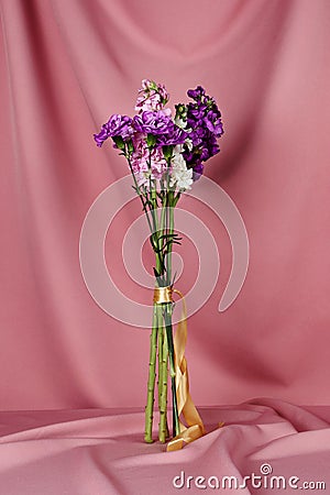 Closeup of a flower bouquet standing a table covered with pink cloth Stock Photo