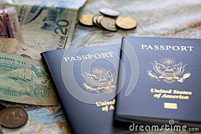 closeup of foreign coins and paper currencies on two American passports laying on large open map Stock Photo