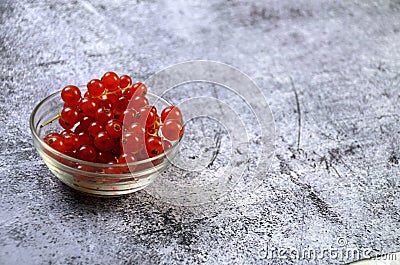 Closeup of the fresh and delicious redcurrants in a glass bowl on a gray surface Stock Photo