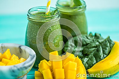 Closeup freshly blended green smoothie with mango and banana in glass jars. Turquoise blue table Stock Photo